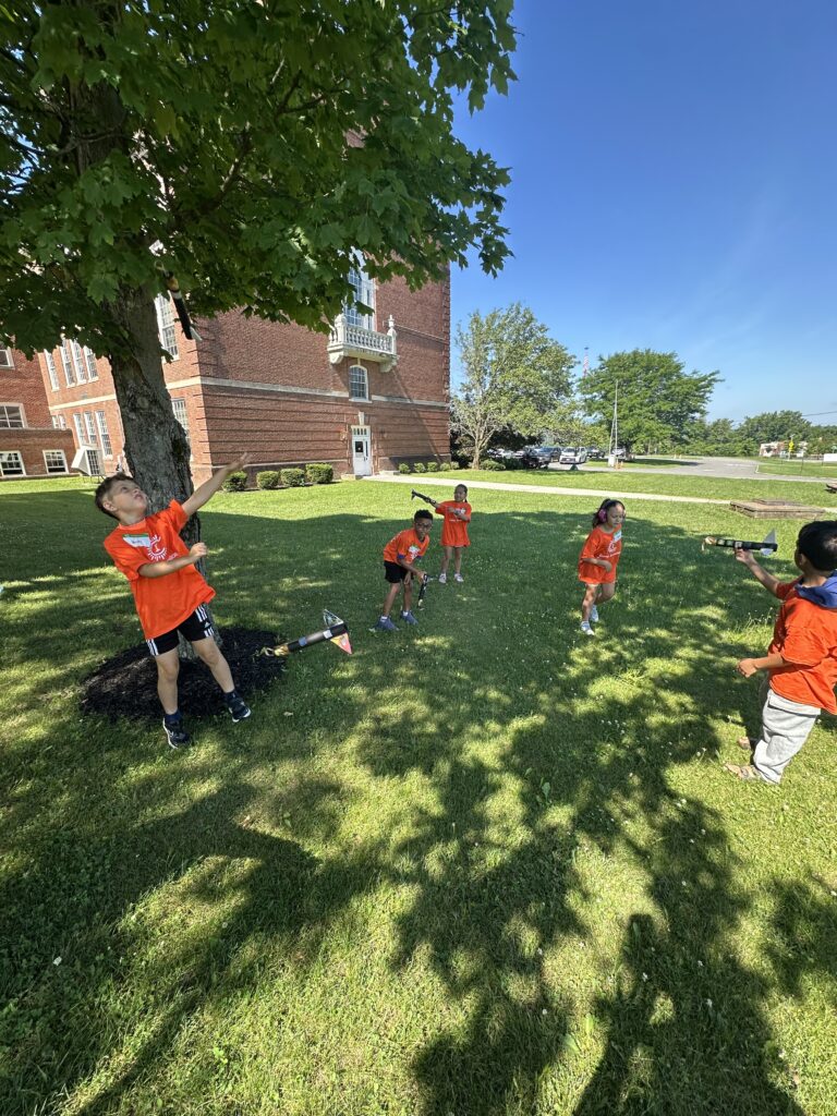 Students participating in an outdoor activity outside of the elementary school on a sunny day. 